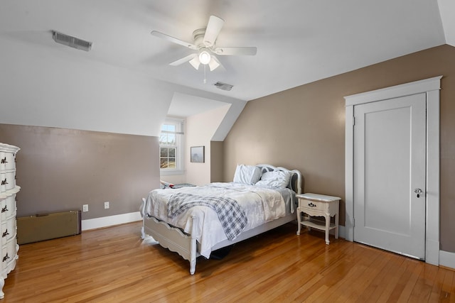 bedroom featuring visible vents, light wood-type flooring, baseboards, and vaulted ceiling