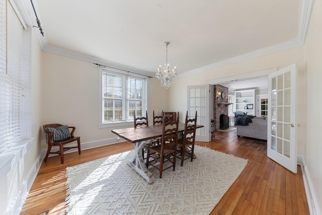 dining area with a chandelier, crown molding, baseboards, and hardwood / wood-style floors