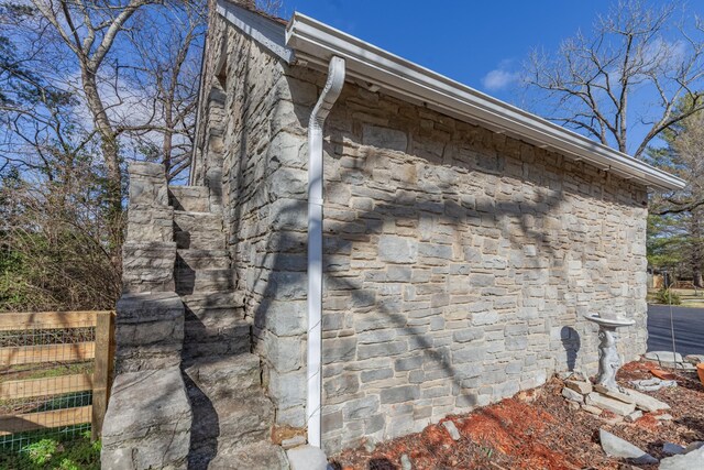 view of home's exterior featuring stone siding and fence