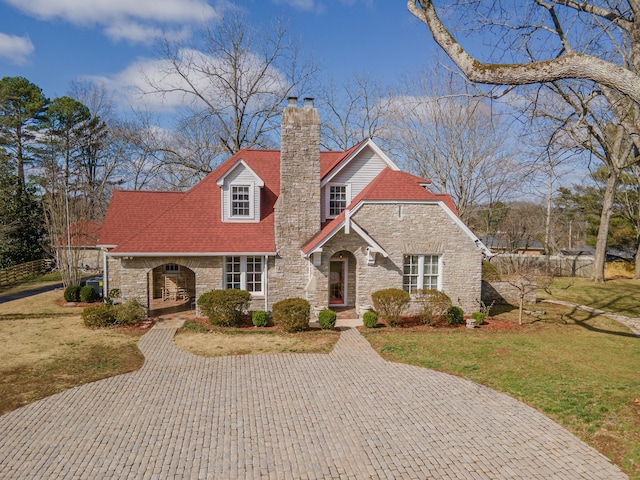 view of front of home featuring stone siding, a chimney, and a front yard