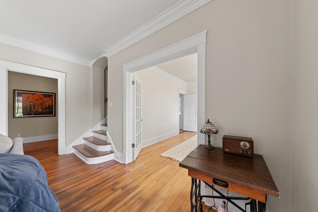 corridor with crown molding, light wood-style flooring, and baseboards