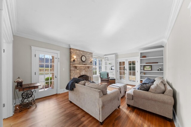 living area featuring french doors, a fireplace, crown molding, and wood finished floors