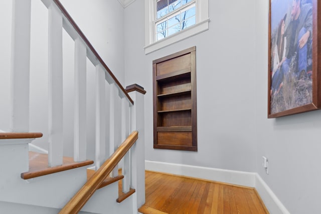 stairs featuring baseboards, built in shelves, and wood-type flooring