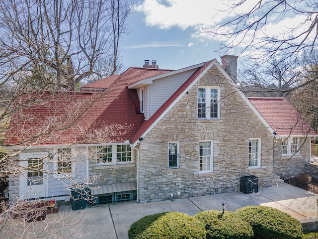 back of property featuring a patio, a chimney, and a shingled roof