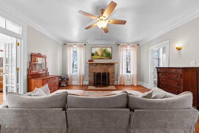 living area featuring baseboards, a fireplace with flush hearth, wood finished floors, and crown molding