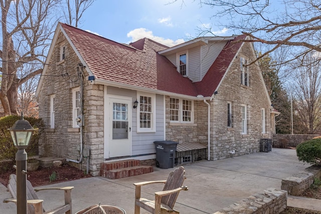 back of property with a patio and stone siding