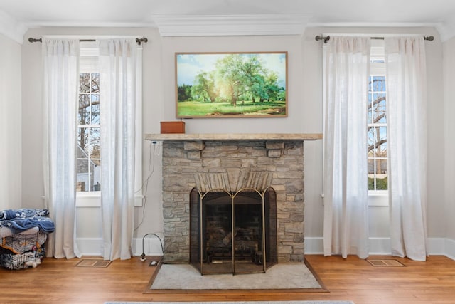 details with wood finished floors, visible vents, baseboards, a fireplace, and crown molding