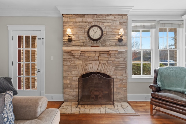 living area featuring a fireplace, wood finished floors, baseboards, and ornamental molding