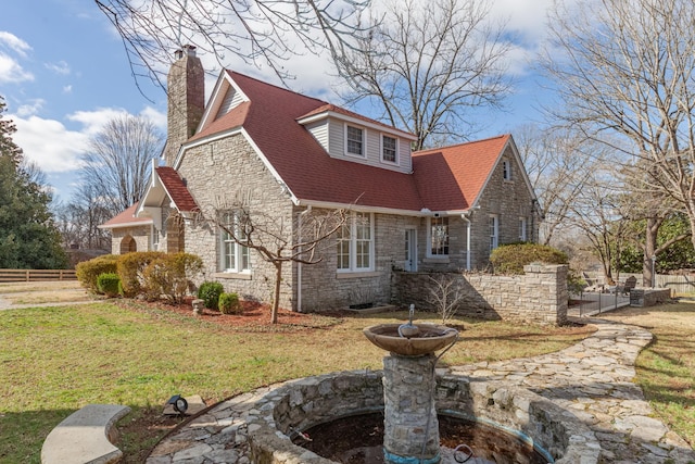 view of property exterior featuring stone siding, a chimney, a yard, and fence