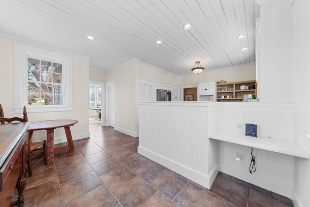 interior space with crown molding, built in desk, wooden ceiling, freestanding refrigerator, and open shelves