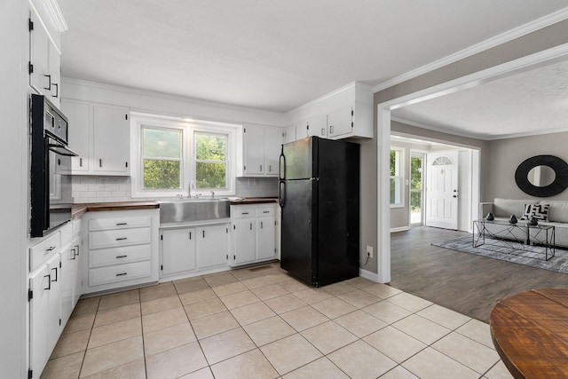 kitchen featuring a wealth of natural light, open floor plan, black appliances, and crown molding