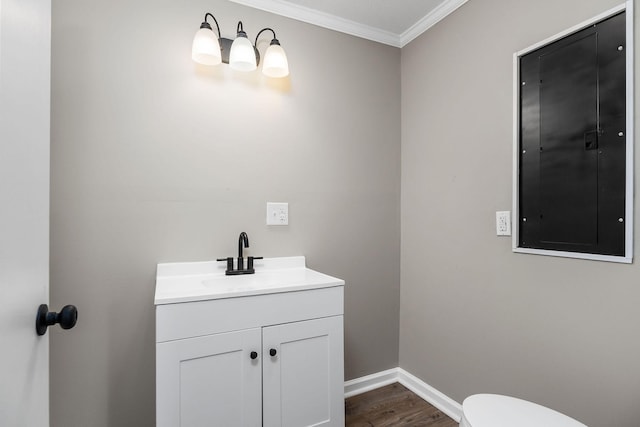 half bath with baseboards, ornamental molding, electric panel, wood finished floors, and vanity