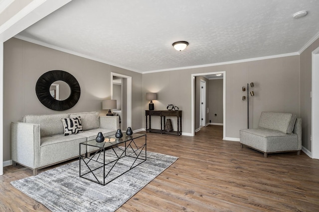 living area featuring a textured ceiling, wood finished floors, baseboards, and ornamental molding