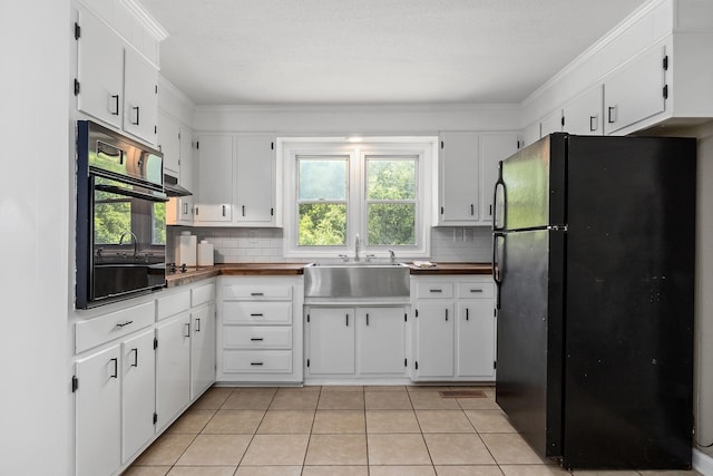 kitchen featuring decorative backsplash, light tile patterned flooring, plenty of natural light, black appliances, and a sink