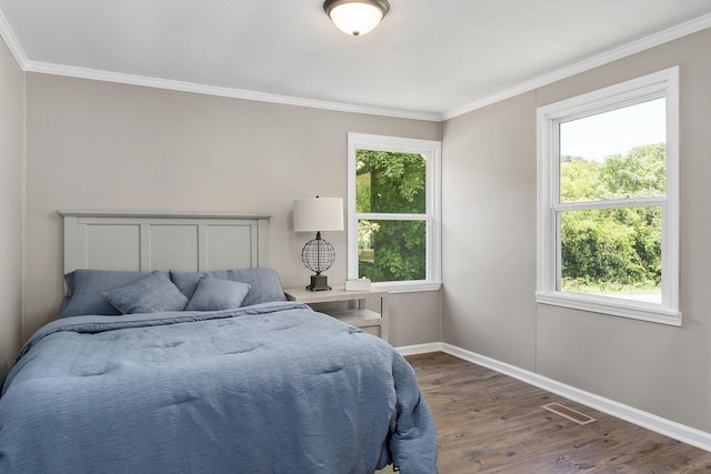 bedroom with visible vents, wood finished floors, baseboards, and ornamental molding