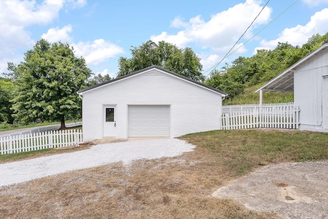 detached garage featuring fence and driveway