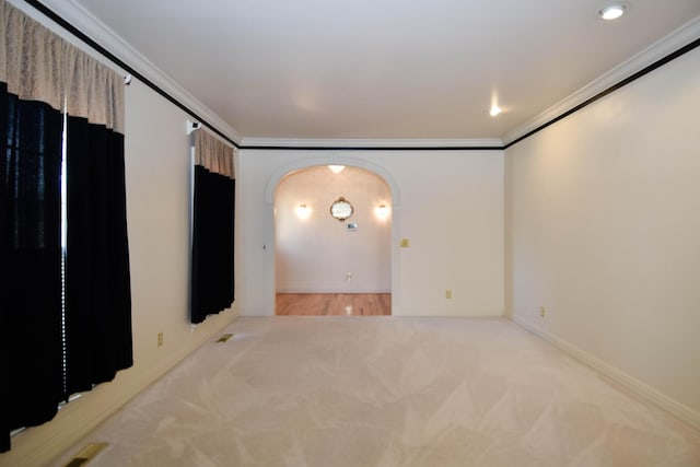 spare room featuring visible vents, arched walkways, carpet, crown molding, and baseboards