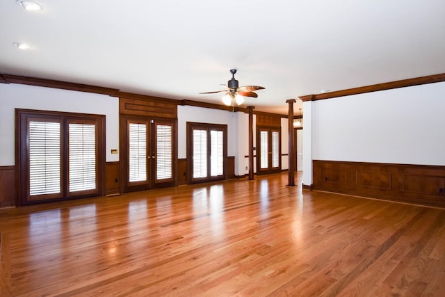 unfurnished living room featuring french doors, a ceiling fan, a wainscoted wall, and light wood finished floors