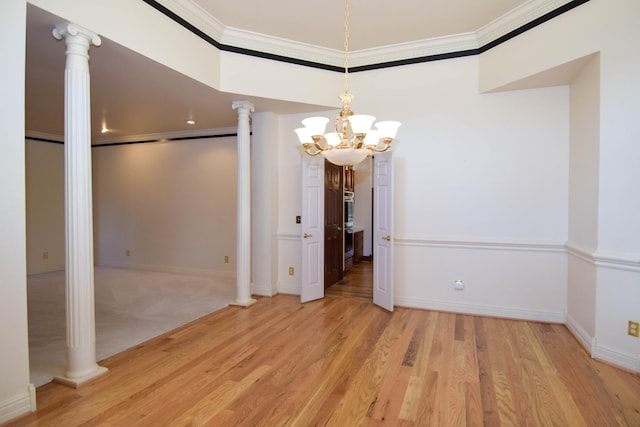 unfurnished dining area featuring wood finished floors, baseboards, decorative columns, crown molding, and a chandelier