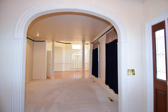 corridor with visible vents, a notable chandelier, light colored carpet, and arched walkways