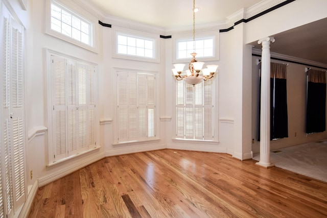 foyer with an inviting chandelier, crown molding, wood finished floors, and ornate columns