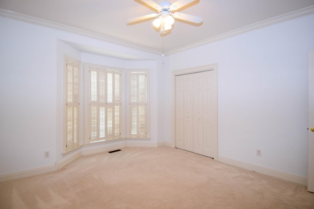 carpeted spare room featuring visible vents, baseboards, and crown molding