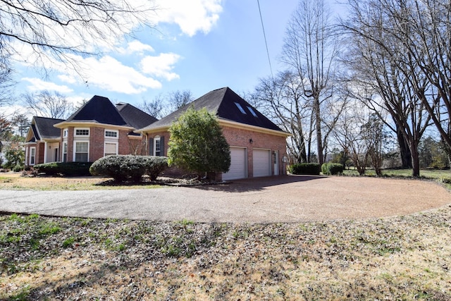 view of side of home with a garage, brick siding, and driveway