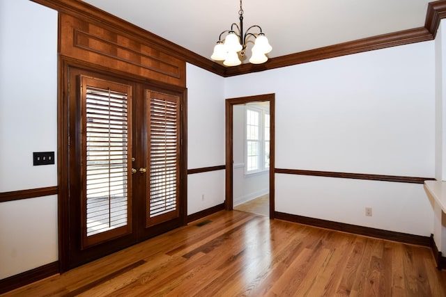 unfurnished room with french doors, baseboards, ornamental molding, and light wood finished floors