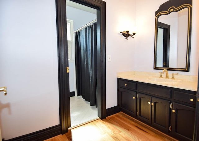 bathroom with baseboards, wood finished floors, and vanity