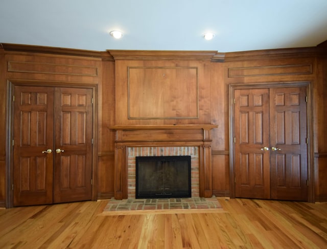 unfurnished living room with light wood finished floors and a brick fireplace