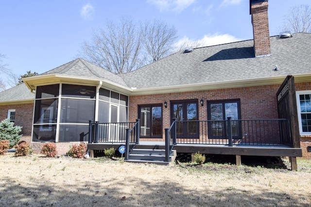 back of property featuring brick siding, a shingled roof, a chimney, and a sunroom