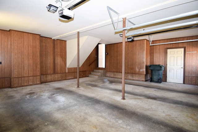 garage with a garage door opener and wood walls