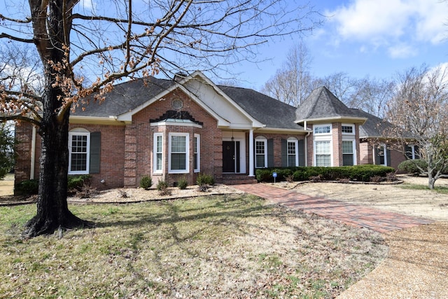 view of front facade featuring a front lawn, brick siding, and roof with shingles