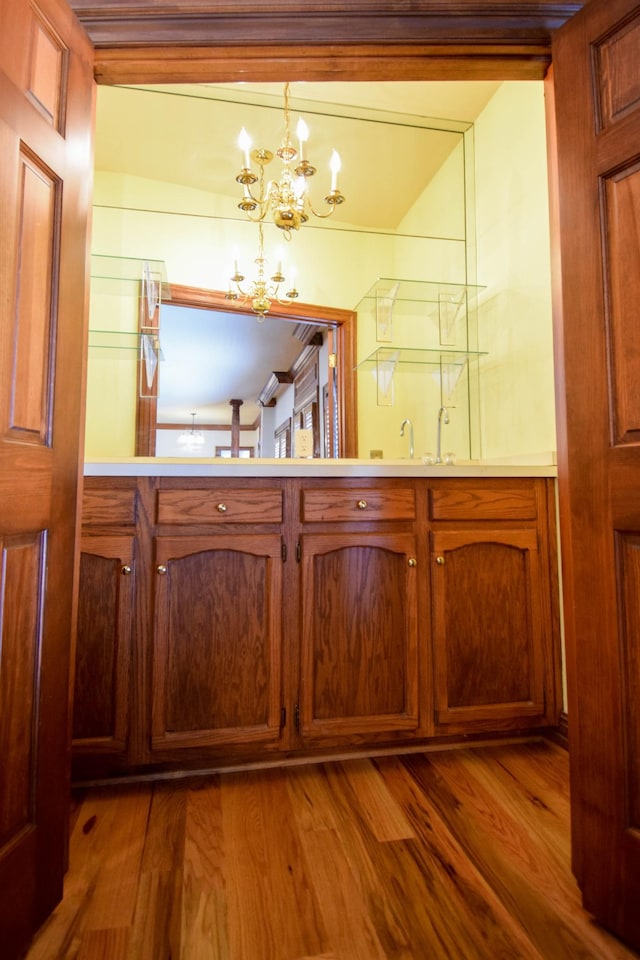 bathroom with a sink, a chandelier, and wood finished floors