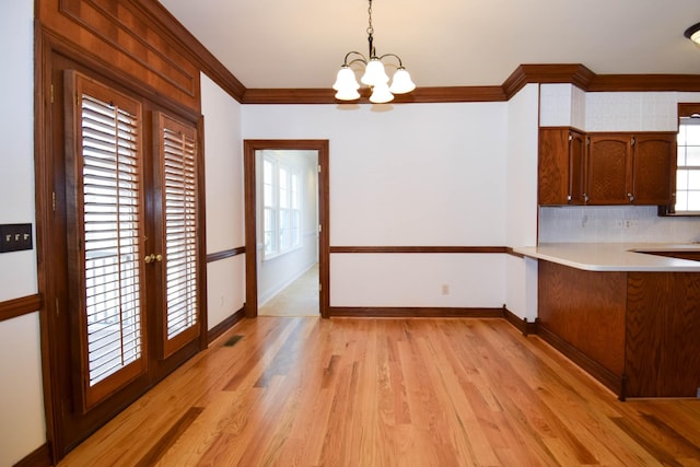 unfurnished dining area with a healthy amount of sunlight, light wood-type flooring, and ornamental molding