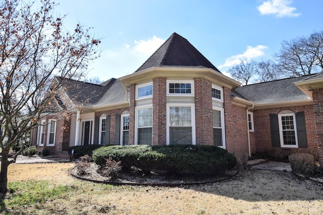 view of side of home with brick siding and roof with shingles