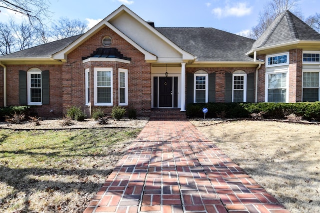 view of front facade featuring brick siding and roof with shingles