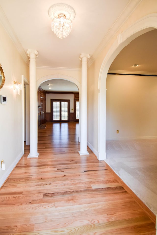 hall with arched walkways, light wood-style flooring, and ornate columns