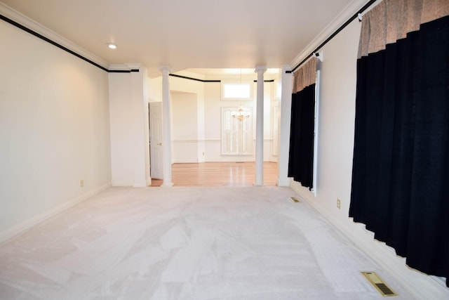 empty room with visible vents, light carpet, ornamental molding, an inviting chandelier, and decorative columns