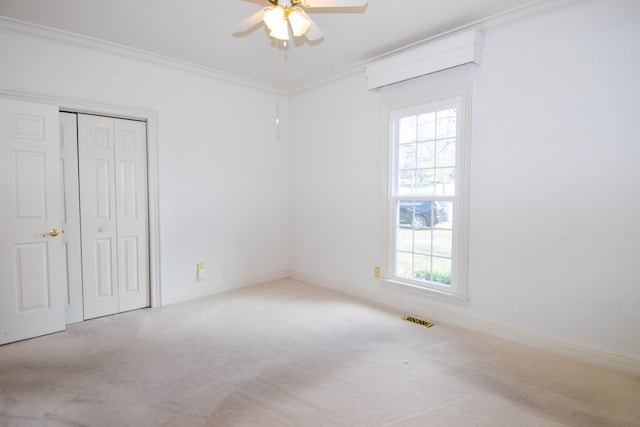 unfurnished bedroom with visible vents, a closet, carpet flooring, and crown molding