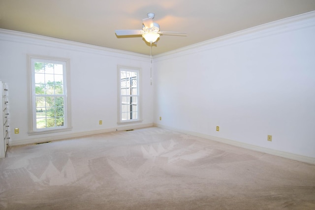 empty room featuring visible vents, light carpet, a healthy amount of sunlight, and crown molding