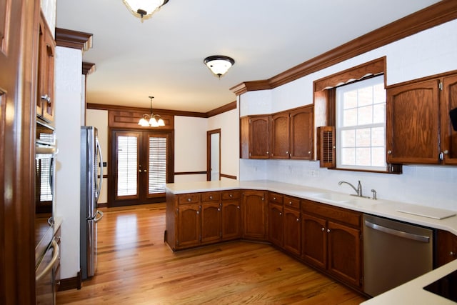 kitchen with light wood finished floors, appliances with stainless steel finishes, a peninsula, and a sink