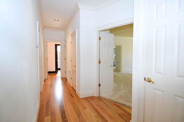 hallway with baseboards, light wood-style floors, and ornamental molding