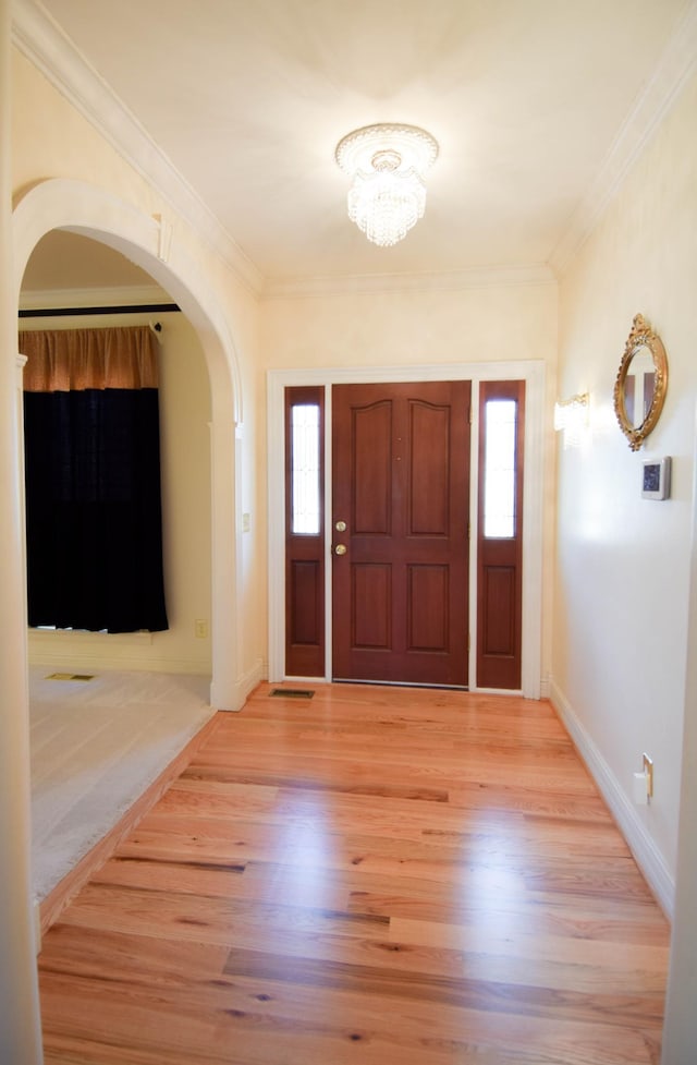 entryway featuring light wood-style floors, baseboards, and ornamental molding