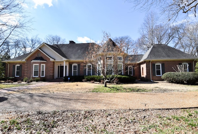 view of front of property featuring brick siding and a chimney