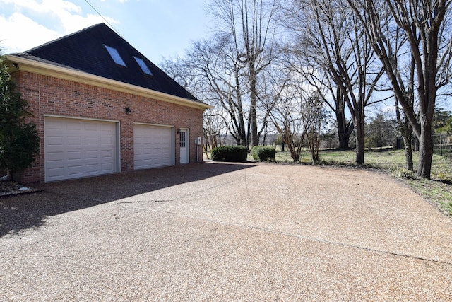 view of side of home featuring brick siding, concrete driveway, and a garage