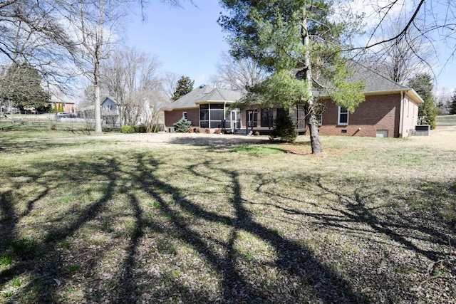 exterior space featuring a lawn, brick siding, a sunroom, and crawl space