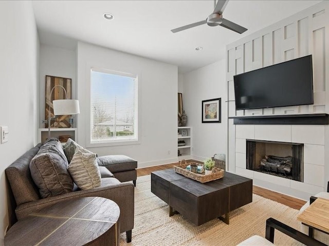 living area with a ceiling fan, recessed lighting, light wood finished floors, baseboards, and a tile fireplace