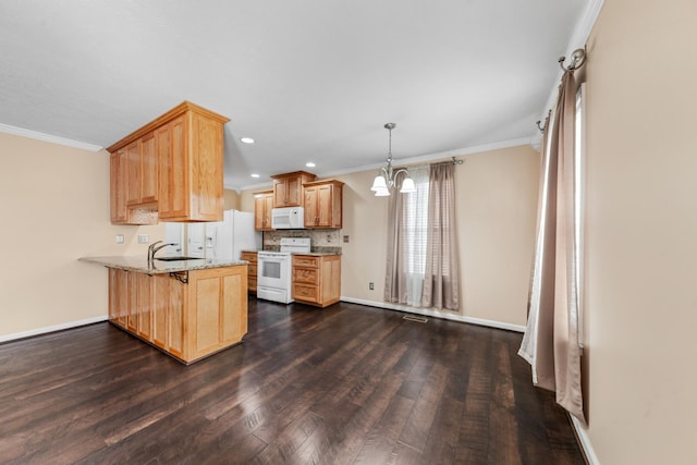 kitchen with a notable chandelier, a sink, dark wood finished floors, white appliances, and a peninsula