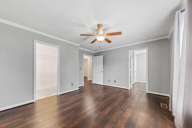 unfurnished bedroom with visible vents, a walk in closet, dark wood-type flooring, and baseboards